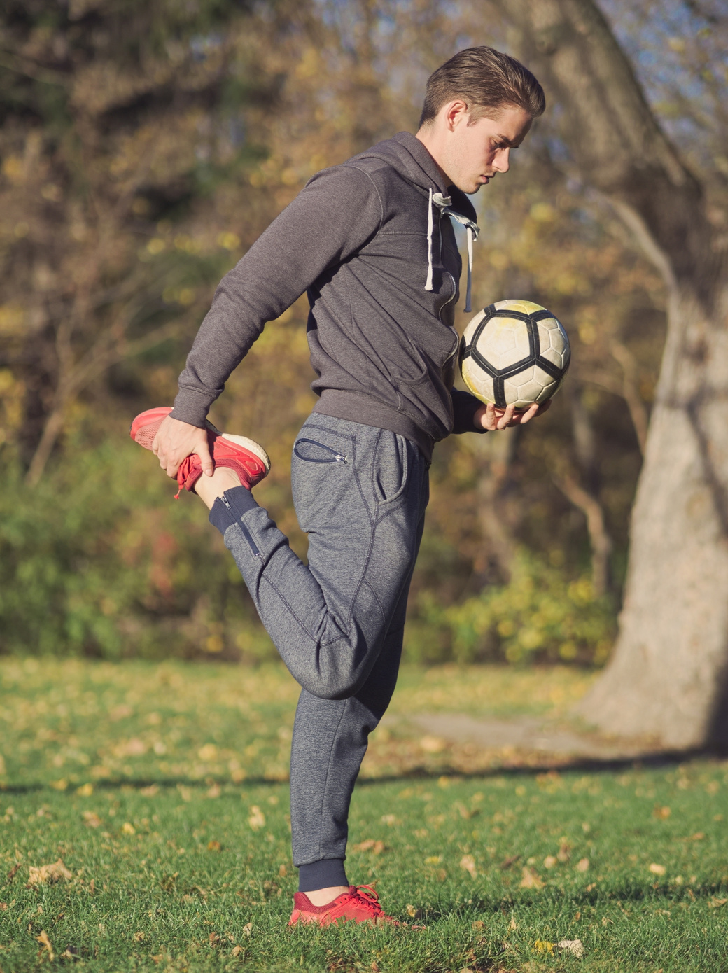 Soccer Player Stretching with Football